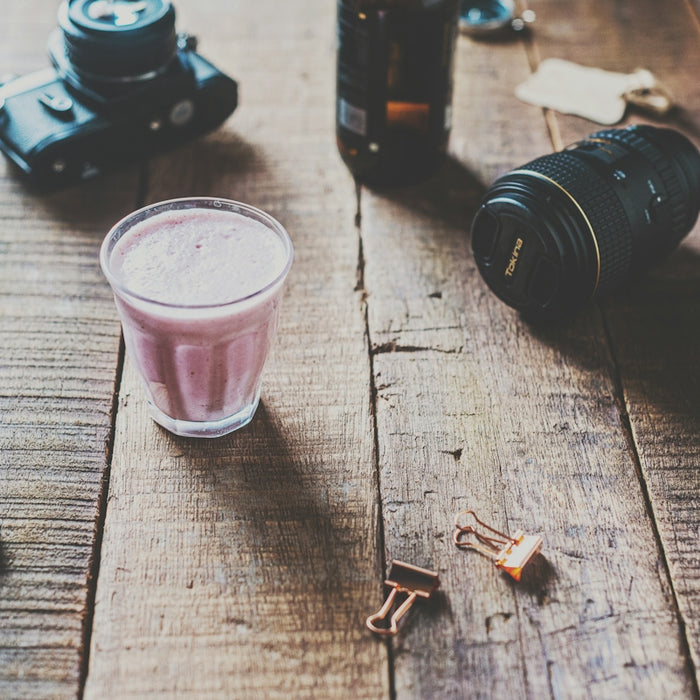 black dslr camera beside pink drinking glass