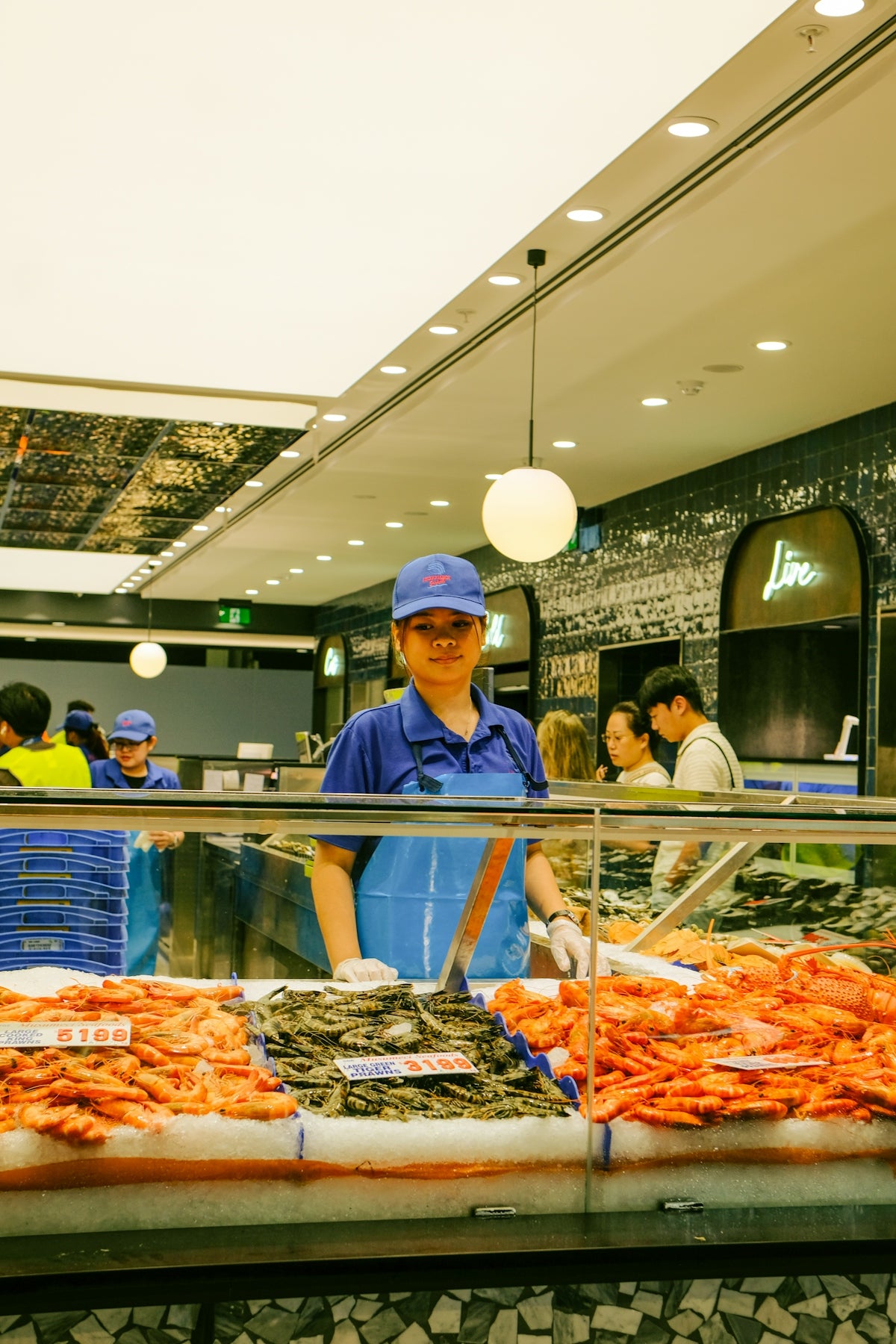 A worker stands behind a seafood display at a market