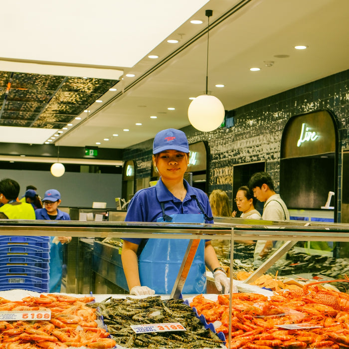 A worker stands behind a seafood display at a market