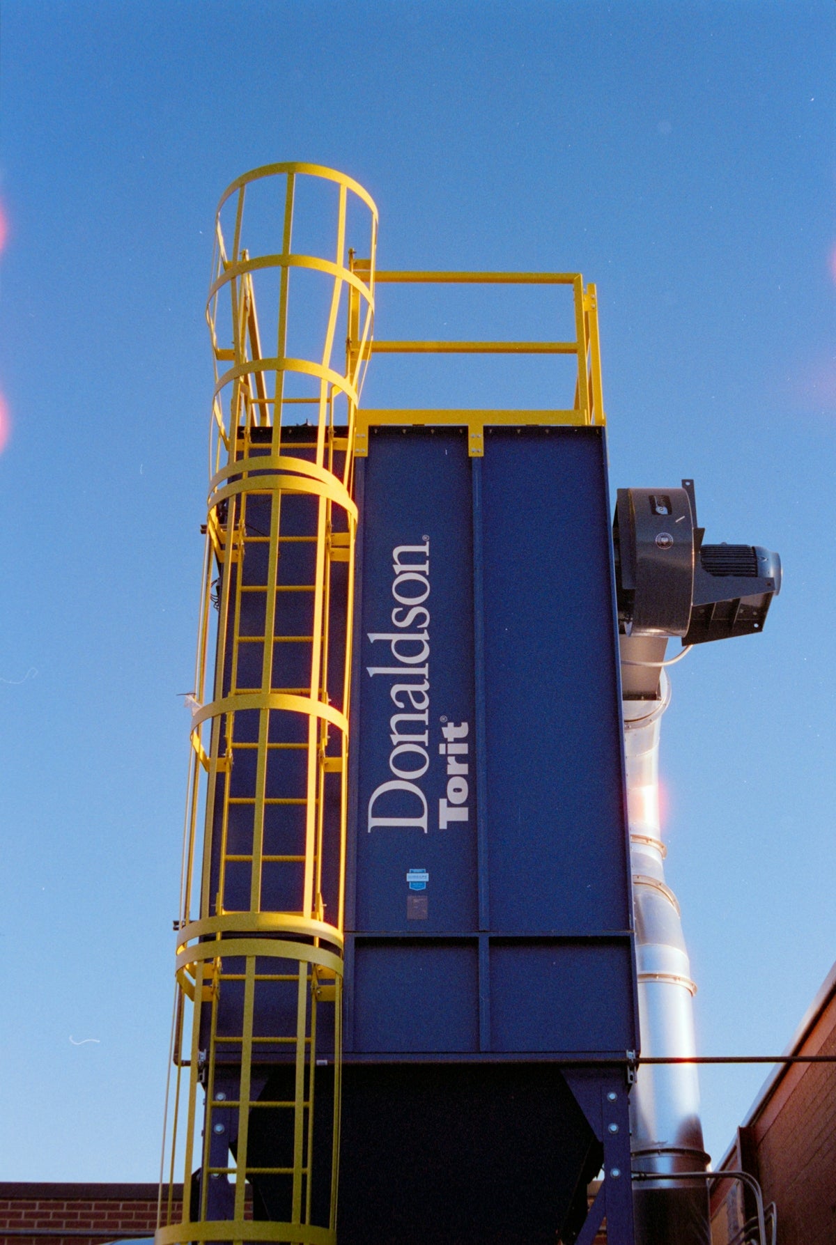 Industrial dust collector with yellow ladder and blue housing