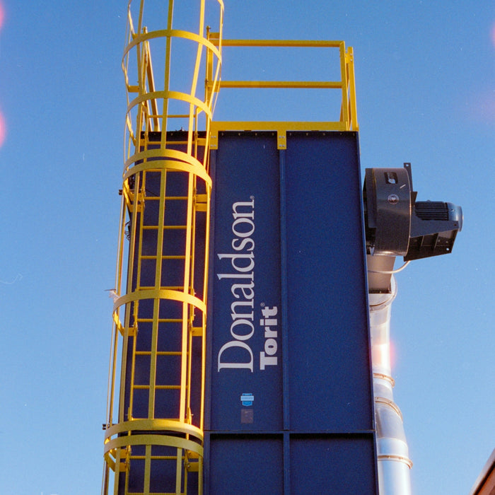 Industrial dust collector with yellow ladder and blue housing